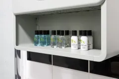 A built-in bathroom storage shelf containing toiletries, bottles and other guest amenities.