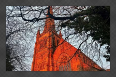 Lancaster Cathedral glowing in a vivid red sunset framed by tree branches