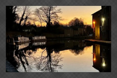 Sunset reflections on the Lancaster Canal with narrowboats and waterside buildings