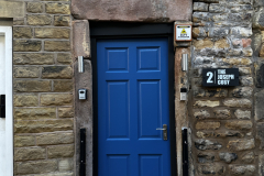 Well-lit entrance doorway to The Joseph Cosy with property sign