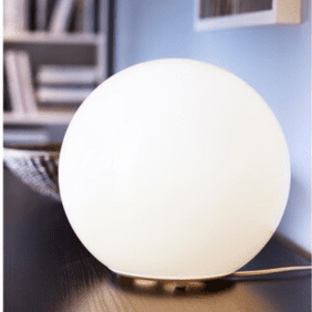 Cozy scene with the FADO lamp on a bookshelf, adding soft lighting.