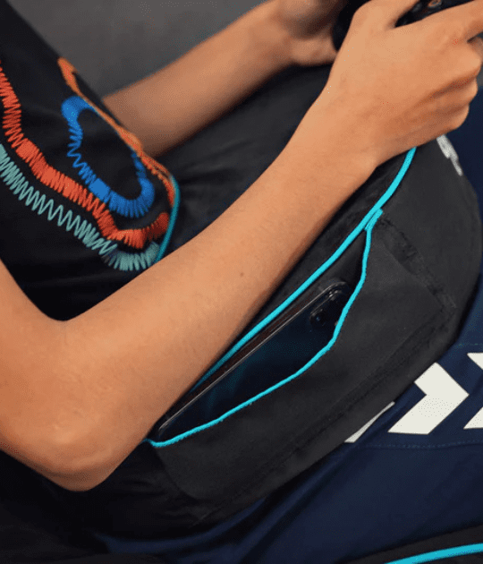 A person using a black and blue gaming support cushion for added comfort while seated.