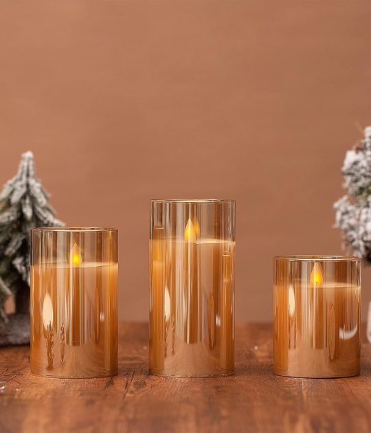 A cozy scene with three LED flameless candles in golden glass holders, set against a warm background.