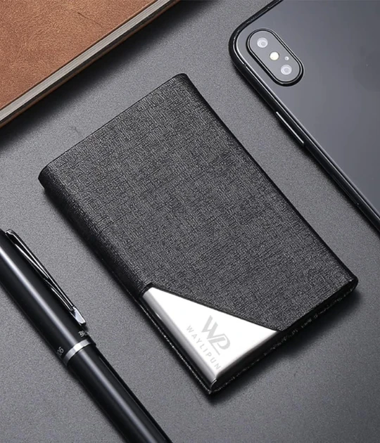 A close-up shot of the cardholder placed on a desk with a pen and phone nearby.