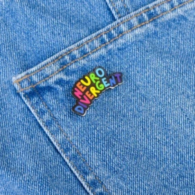 A colorful enamel pin with the words 