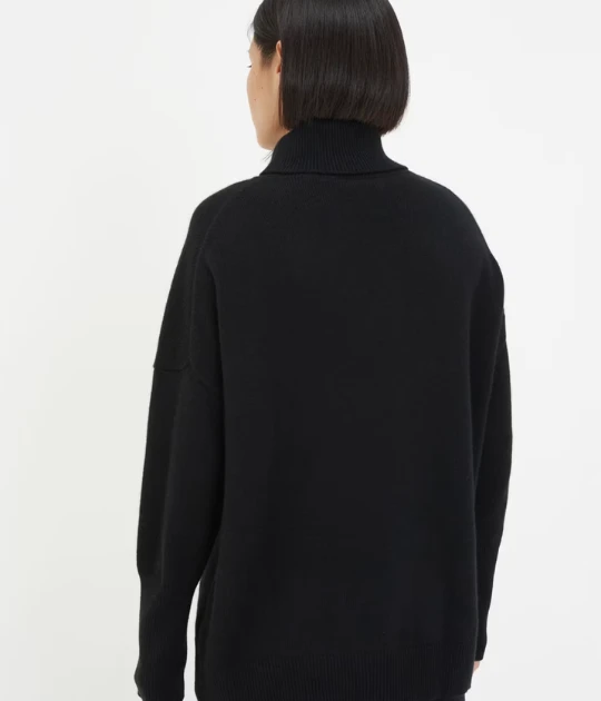 A back view of the same turtleneck sweater, highlighting its high neckline and draped silhouette for a timeless and chic style.